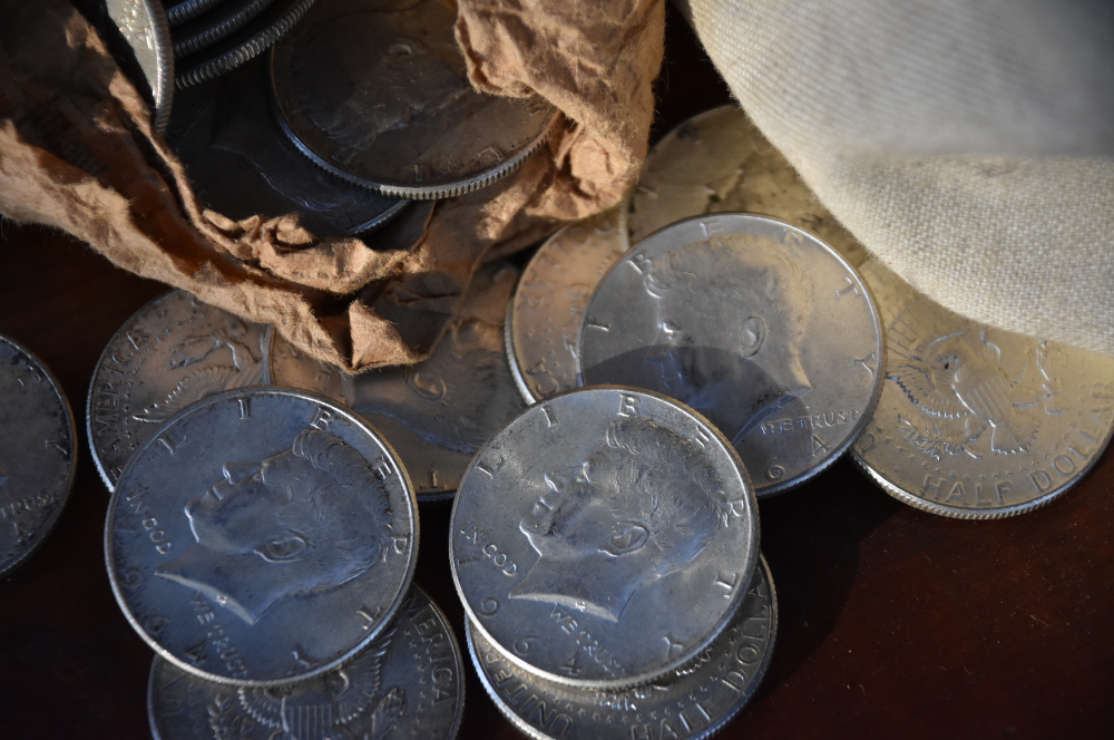 Kennedy half dollars spilling from a paper roll on a table – Coin Buyers in Tyler.